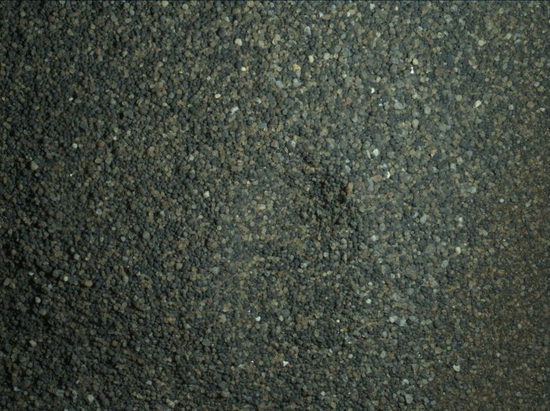1月22日晚间，好奇号机械臂末端的成像仪(MAHLI)在自带照明灯的帮助下，拍摄的一片邮票大小的地面，能看到未通过滤网（滤眼150微米）而被丢弃至的沙粒。