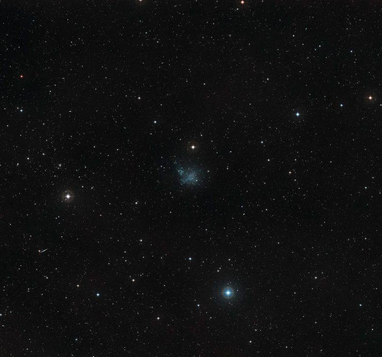 在这张数字巡天计划拍摄的广角照片中， 可以看到IC 1613周围的天空。照片中央形状不规则如同黯淡恒星的天体正是IC 1613。
