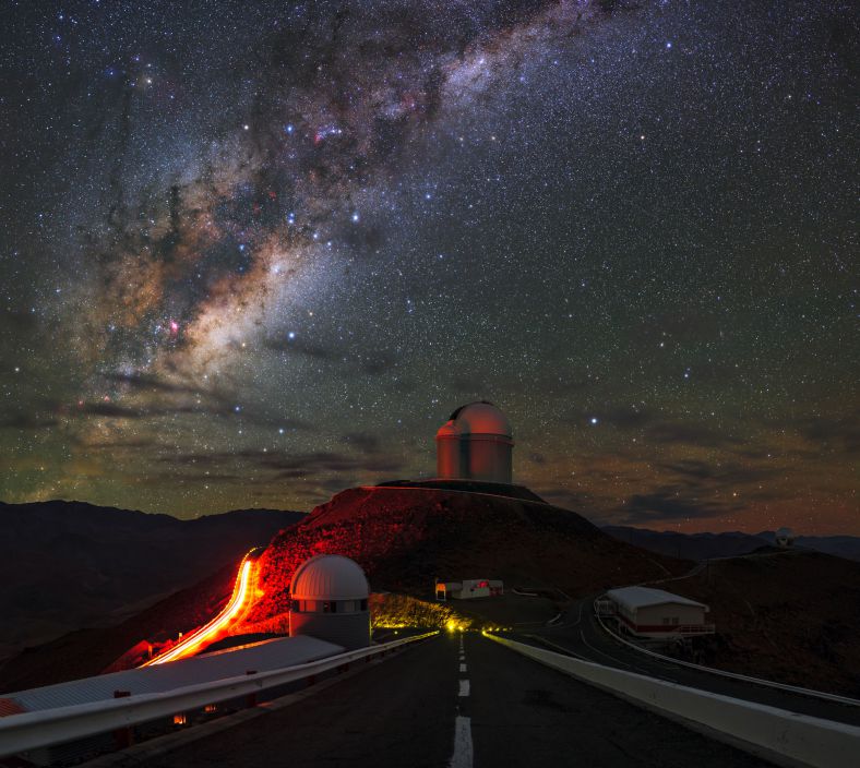 这是欧洲南方天文台位于智利的拉西拉天文台，银河从安第斯山脉上方伸展而出横跨夜空。中央的道路通往拉西拉天文台，沿途坐落着各种先进的天文望远镜，它们瞄向银河系，但视野已经超出很远。