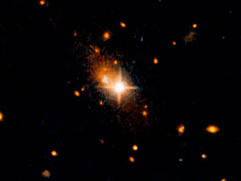 图片中央明亮的类似星星的天体就是此次发现的类星体，这是黑洞存在的信号。它背后则是相对黯淡的主星系。 