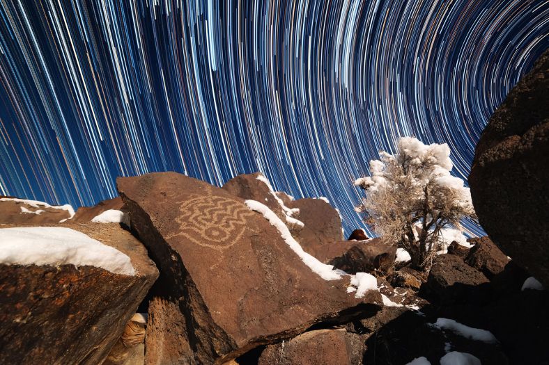 美国犹他州西部的沙漠，在部分玄武岩巨石上能看到一些岩画。摄影师试图用天体运动形成的星轨来陪衬这幅具有动态效果的岩画作品。
