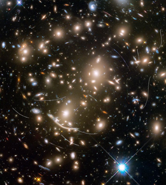 星系团 Abell 370距离地球40亿光年之遥，位于鲸鱼座方向，其中包含数百个星系，星系之间的引力让它们抱成一团。在上面照片中，22道白色的轨迹是5颗意外入镜的小行星的杰作，它们都太过暗弱，此前并未被天文学家发现过。